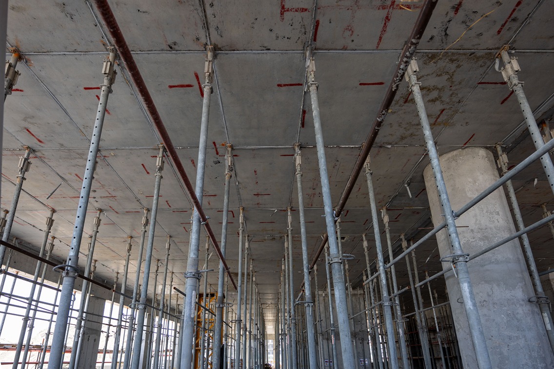 Beach Walk Iii By Imtiaz Interior view of a construction site showing vertical support beams, scaffolding, and concrete ceilings under construction.