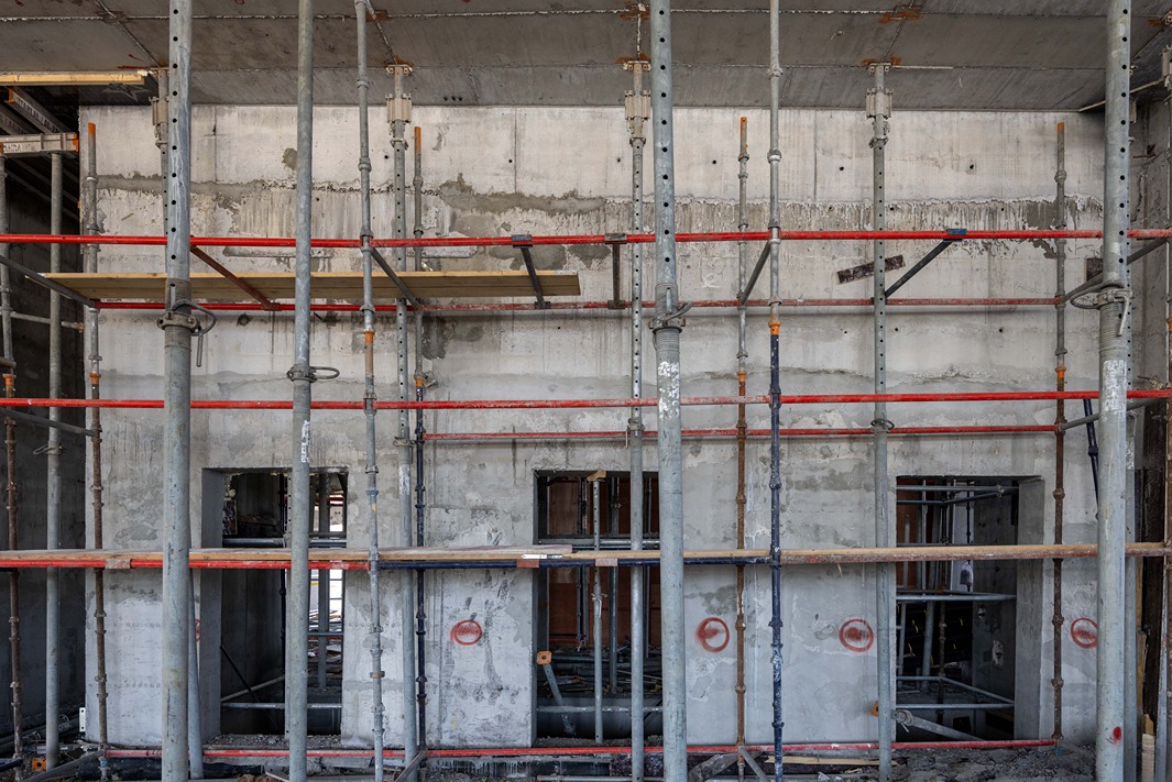 Beach Walk Iii By Imtiaz A construction site featuring a concrete wall supported by metal scaffolding and beams, with visible openings and raw materials.