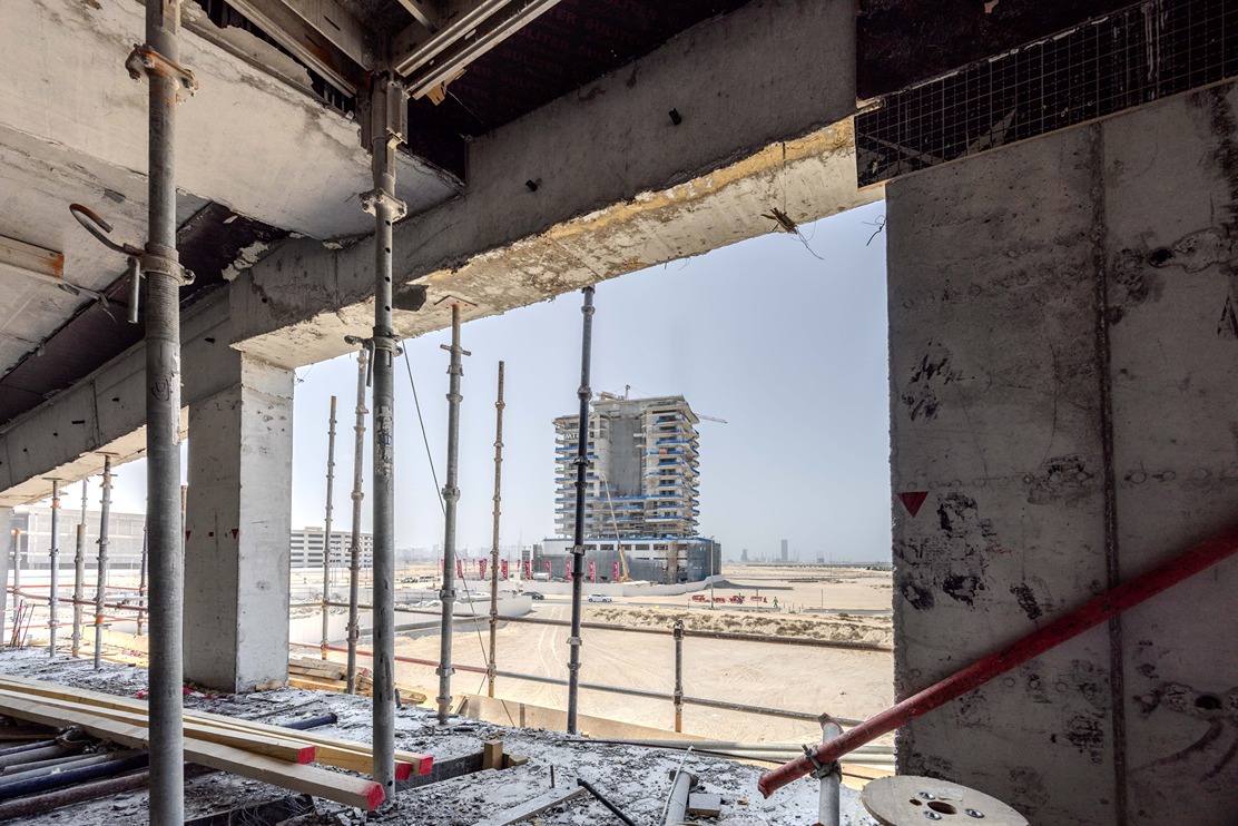 Beach Walk Iii By Imtiaz View from a construction site featuring scaffolding and a partially built high-rise building in the distance.