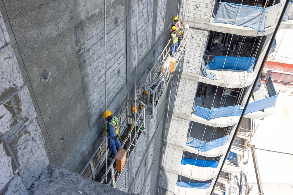 Beach Walk Residence Workers in hard hats are using scaffolding to perform construction on a high-rise building's exterior wall.