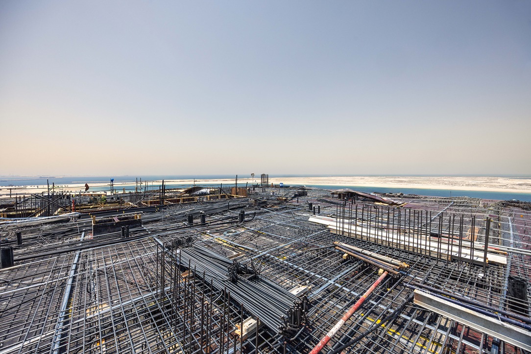 Beach Walk Iii By Imtiaz View of a construction site with steel rebar frameworks and a distant ocean horizon under a clear sky.