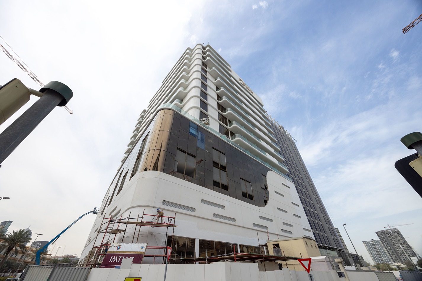 Pearl House By Imtiaz A modern, multi-story building under construction, featuring white and dark glass facades with scaffolding around it.