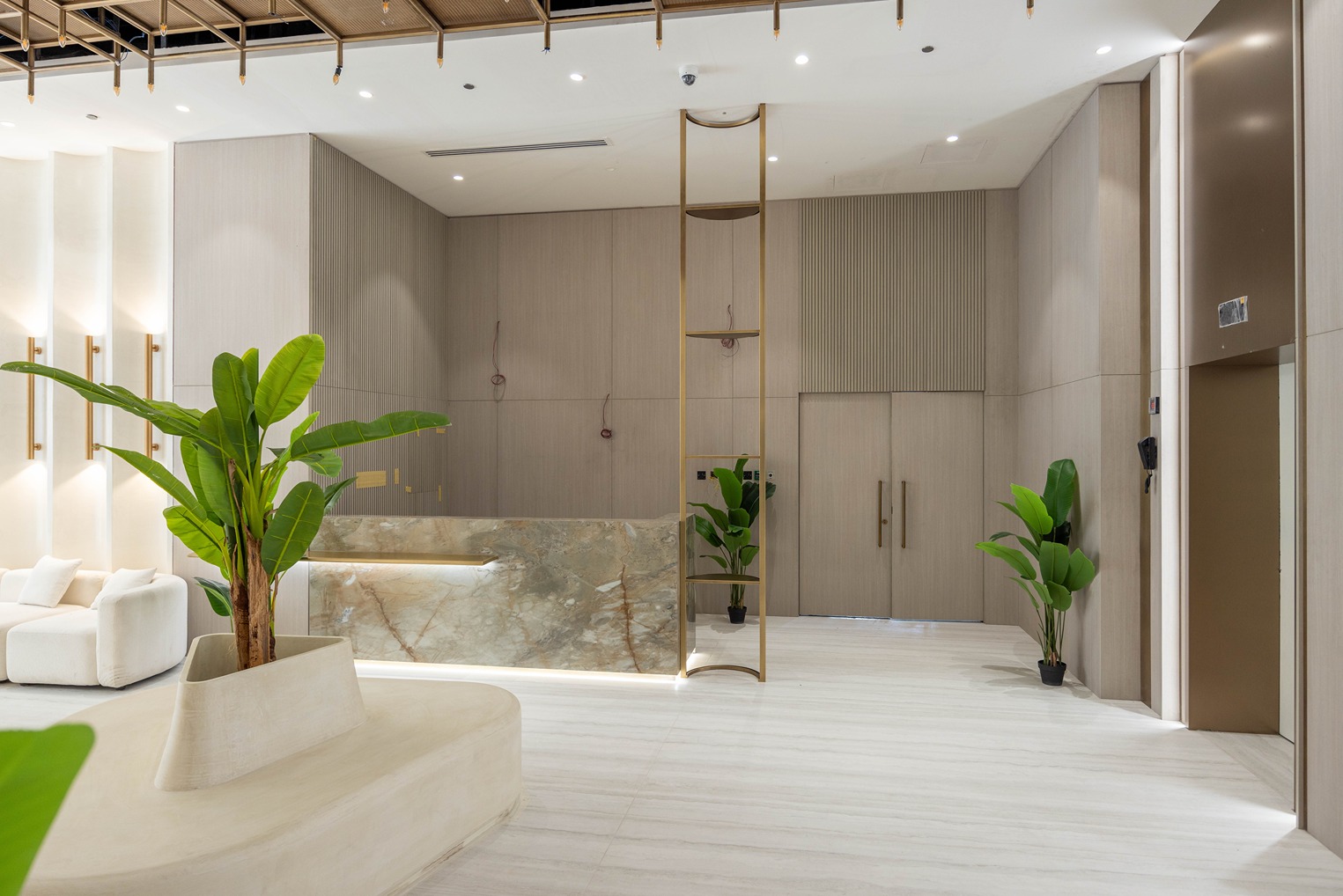 Pearl House By Imtiaz A modern lobby featuring a marble reception desk, elegant plants, and stylish seating with warm lighting.