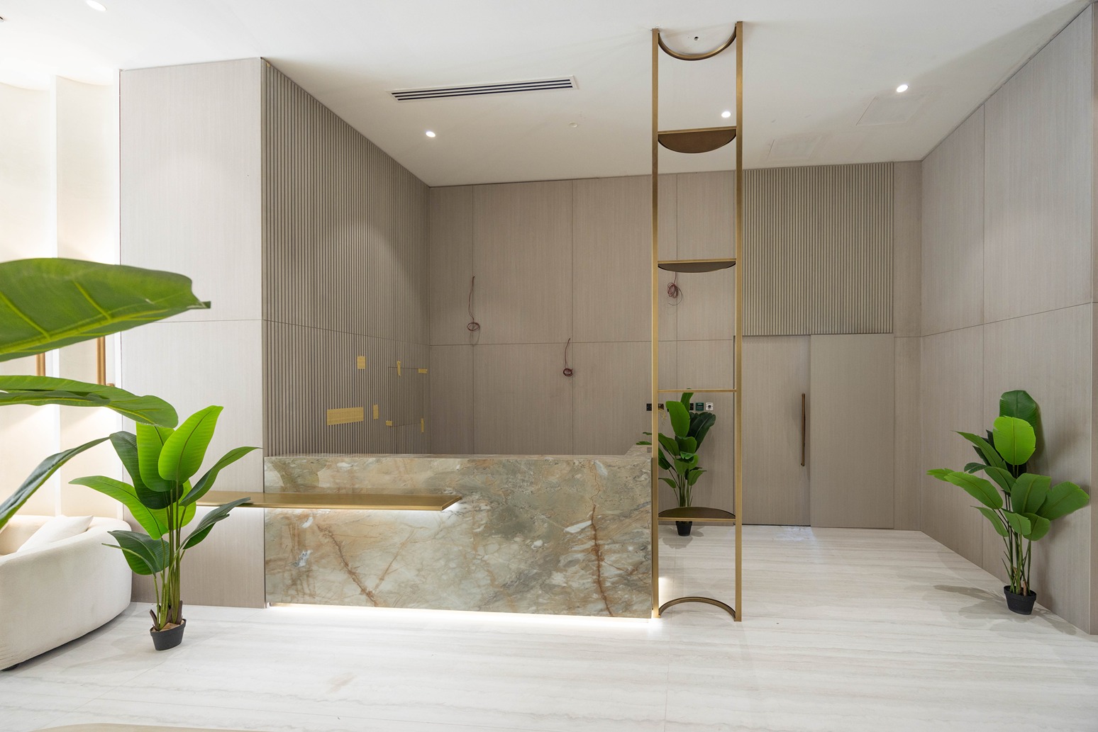 Pearl House By Imtiaz Modern reception area featuring a marble front desk, potted plants, and light wood accents. Bright and elegant design.