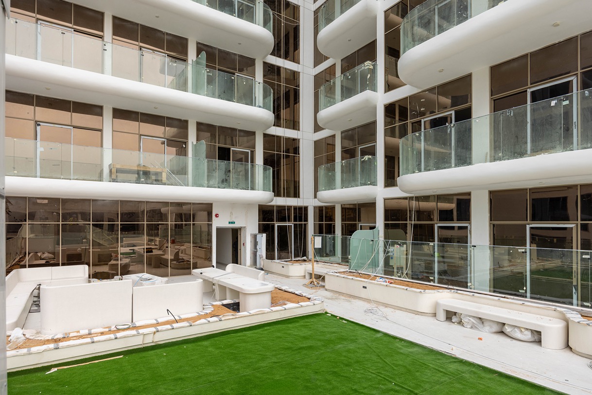 Pearl House By Imtiaz An unfinished interior space featuring empty balconies, glass walls, and artificial grass on the ground.
