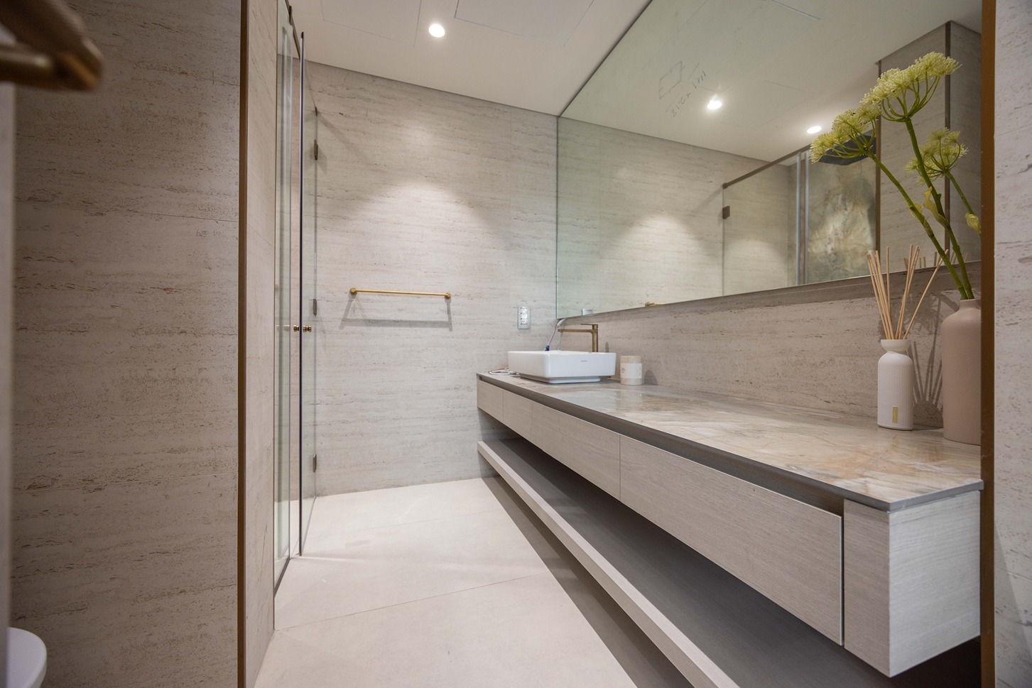 Pearl House By Imtiaz A modern, minimalist bathroom featuring a glass shower, stone walls, a sleek counter, and decorative plants.