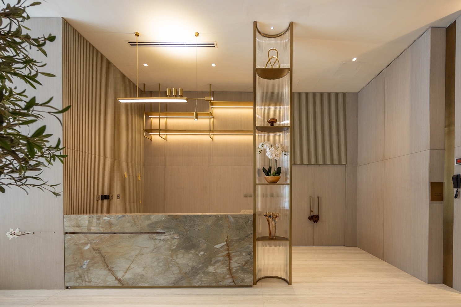 Pearl House By Imtiaz A modern reception area featuring a marble desk, decorative plants, and stylish lighting in a minimalistic setting.