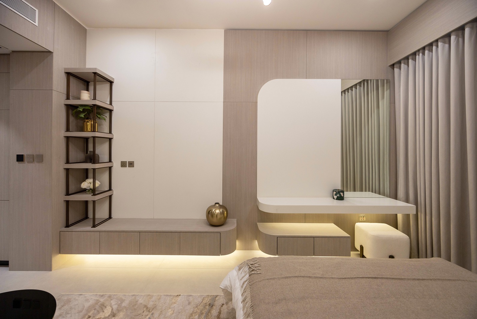 Pearl House By Imtiaz A modern bedroom featuring neutral tones, a sleek wall shelf, a minimalist desk, and elegant curtains.