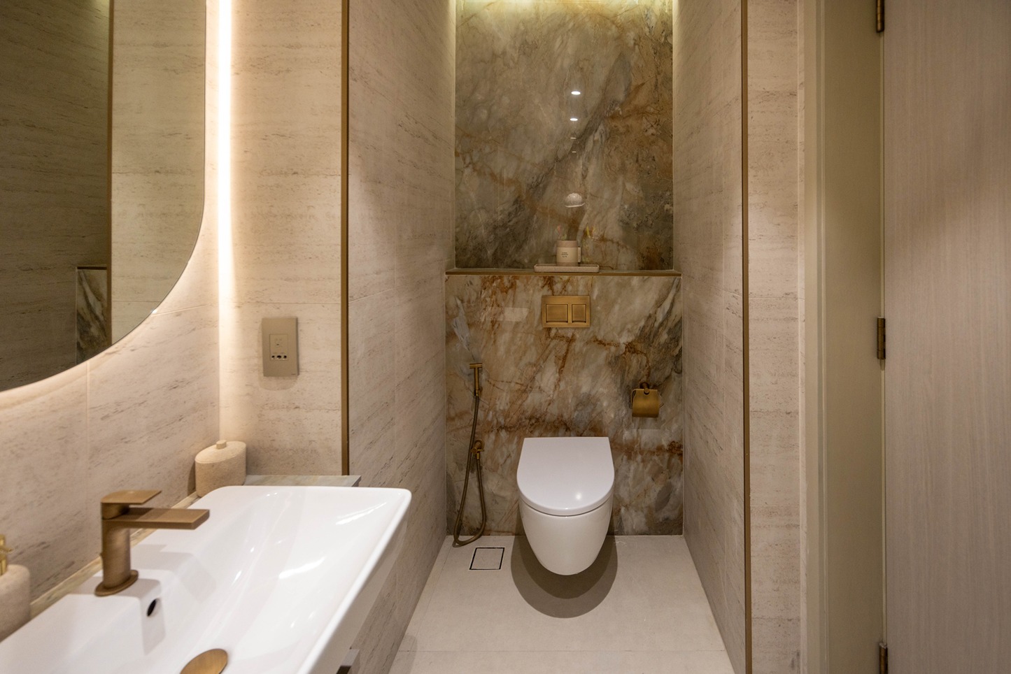 Pearl House By Imtiaz A modern bathroom featuring a clean design with a white sink, toilet, and stylish marble walls.