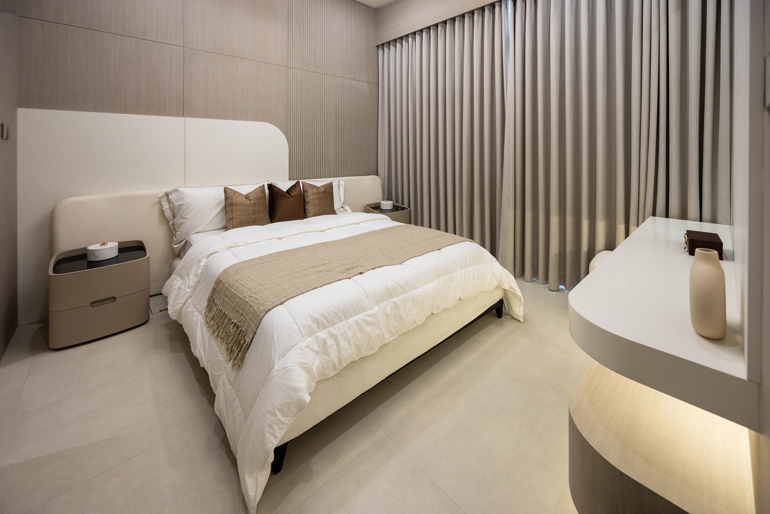 Pearl House By Imtiaz A modern bedroom featuring a bed with white linens, decorative pillows, and a light wood accent wall.