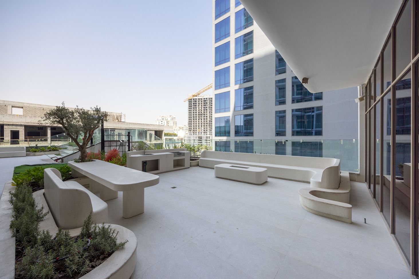 Pearl House By Imtiaz A modern outdoor space featuring sleek furniture, planters, and buildings in the background under a clear sky.