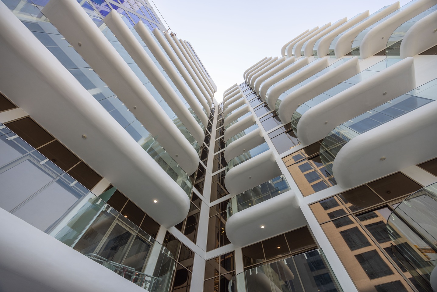 Pearl House By Imtiaz A modern architectural view of a building's facade with balconies and glass windows, captured from below.
