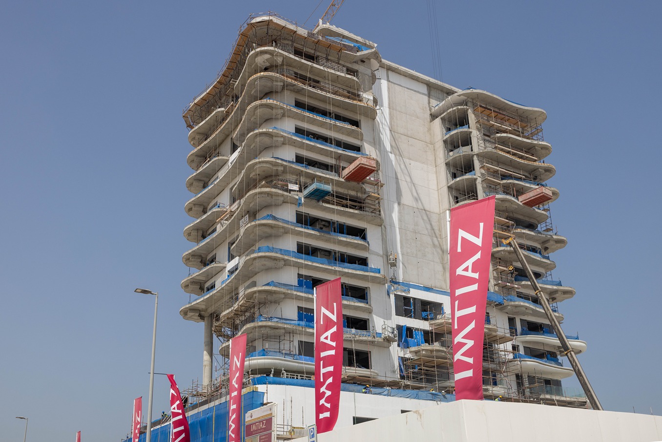 Beach Walk Residence A partially constructed multi-story building with scaffolding and large red banners displaying "IMTIAZ."