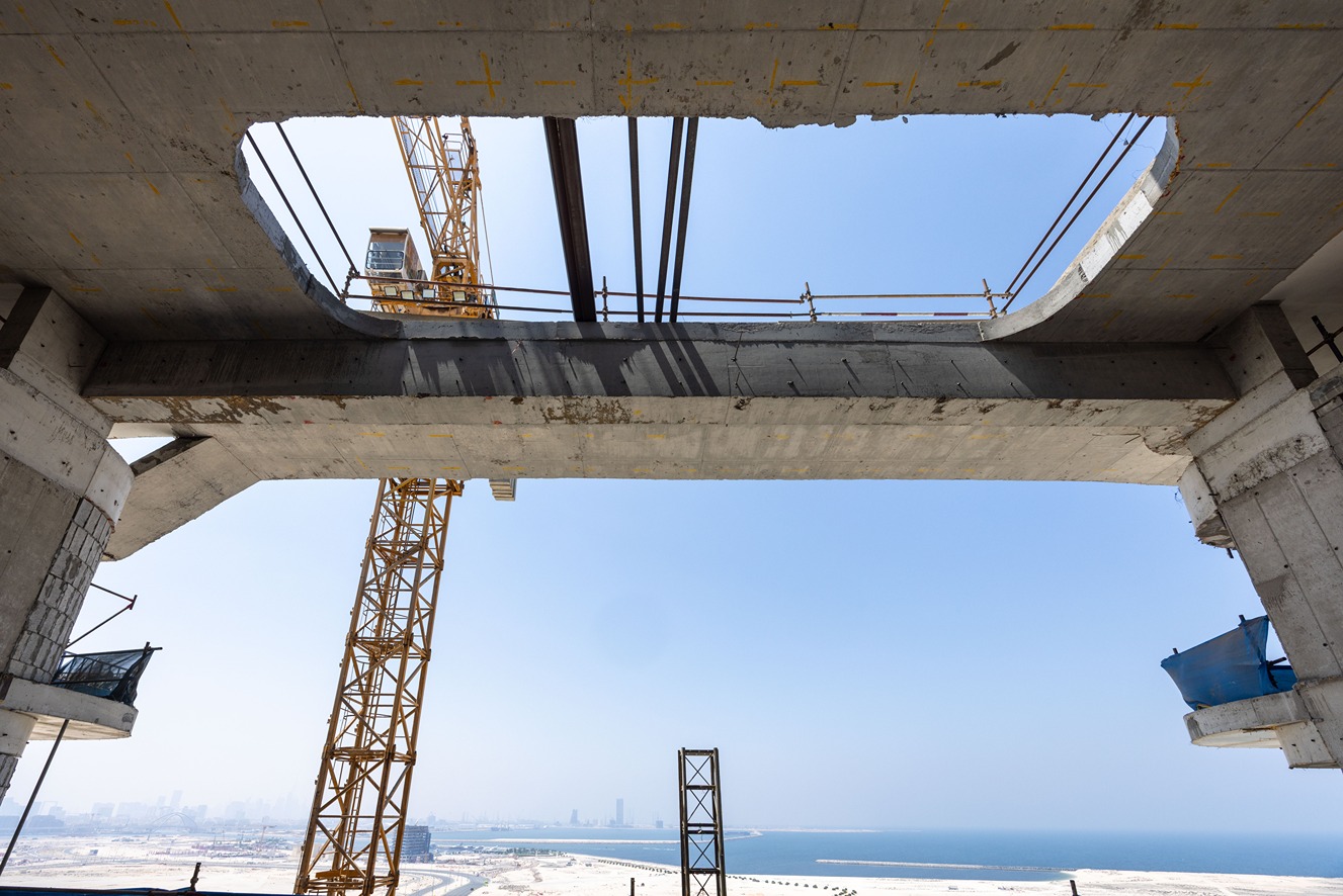 Beach Walk Residence A view of a construction site with a crane and a large concrete structure under a clear blue sky.