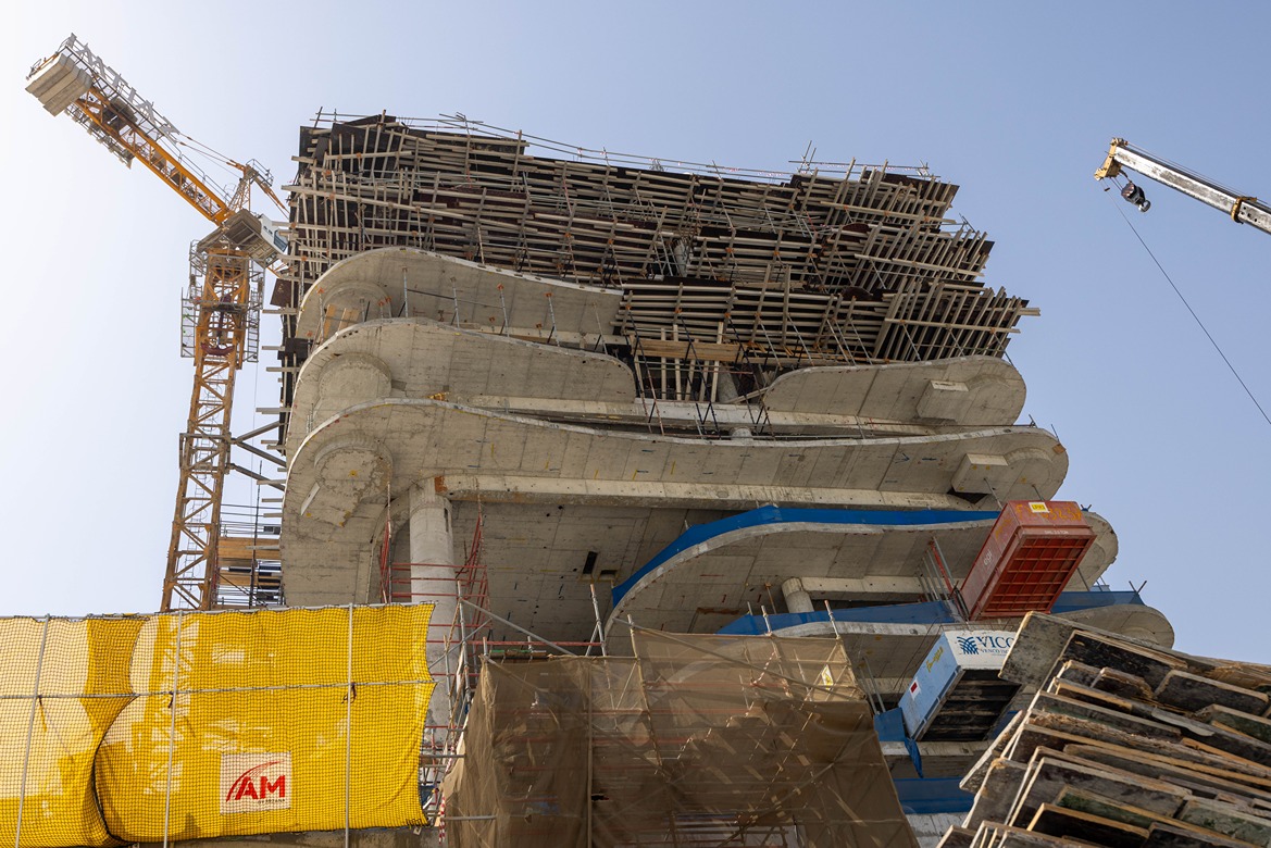 Beach Walk Iii By Imtiaz Construction site featuring a tall building framework with scaffolding, cranes, and concrete structures against a clear sky.