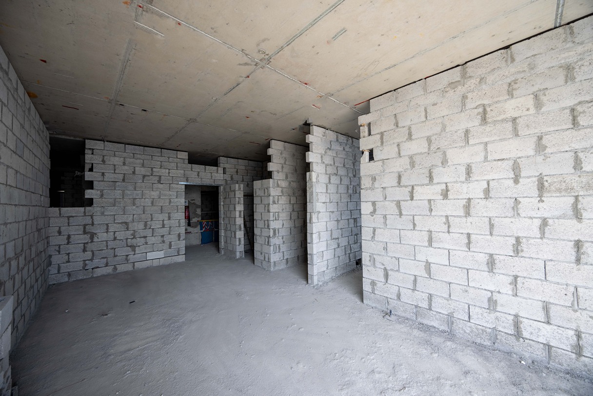 Beach Walk Iii By Imtiaz An unfinished interior space with gray cinder block walls and a concrete ceiling, featuring an unpolished floor.