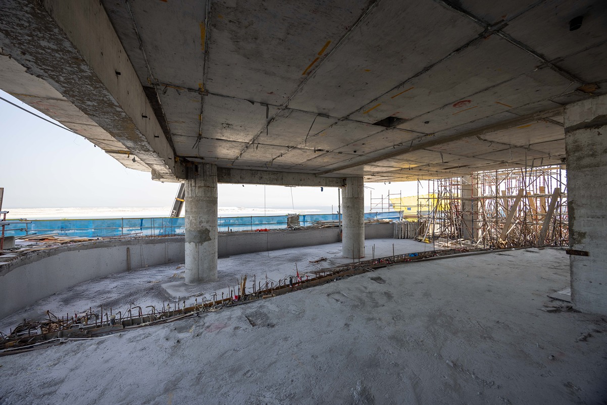 Beach Walk Iii By Imtiaz An unfinished interior of a building under construction, featuring exposed beams, concrete pillars, and scaffolding.