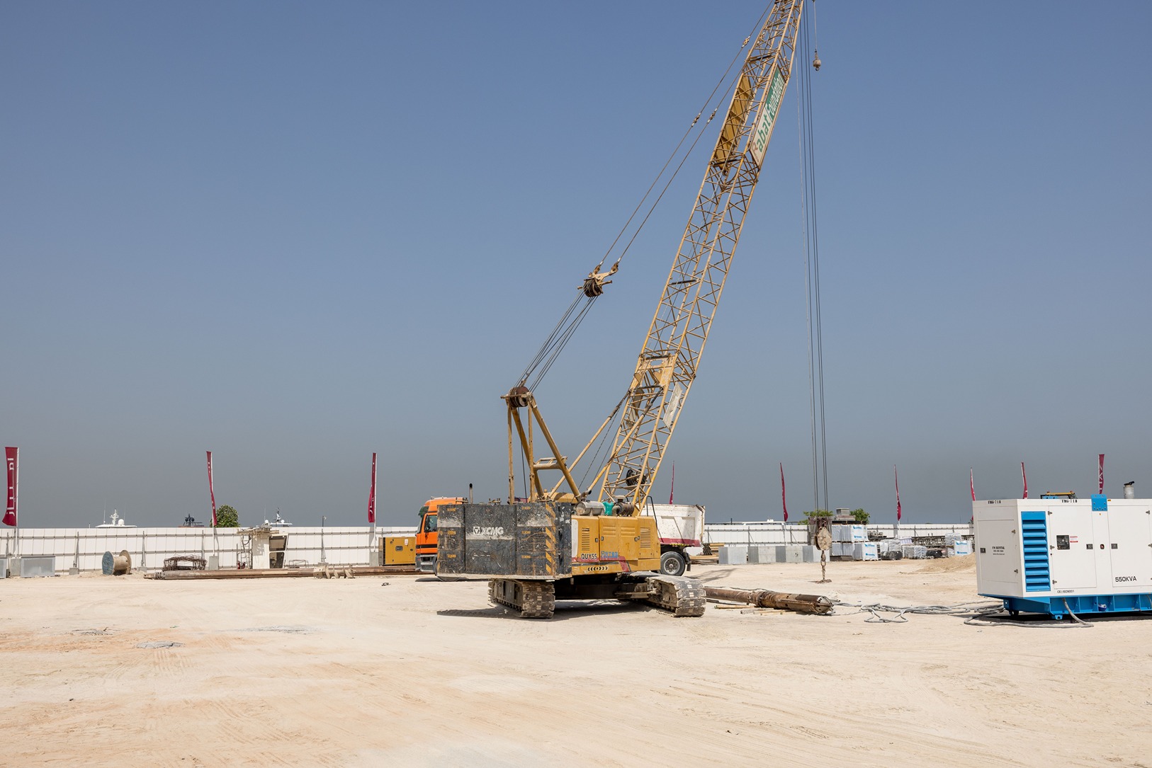 Cotier House 2 By Imtiaz A construction site featuring a large yellow crane, construction equipment, and a clear blue sky in the background.