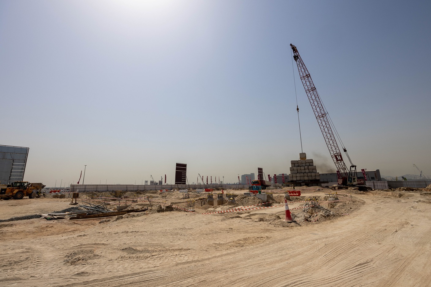 Cotier House 2 By Imtiaz Construction site with a crane lifting blocks, machinery, and unfinished structures under a clear sky.