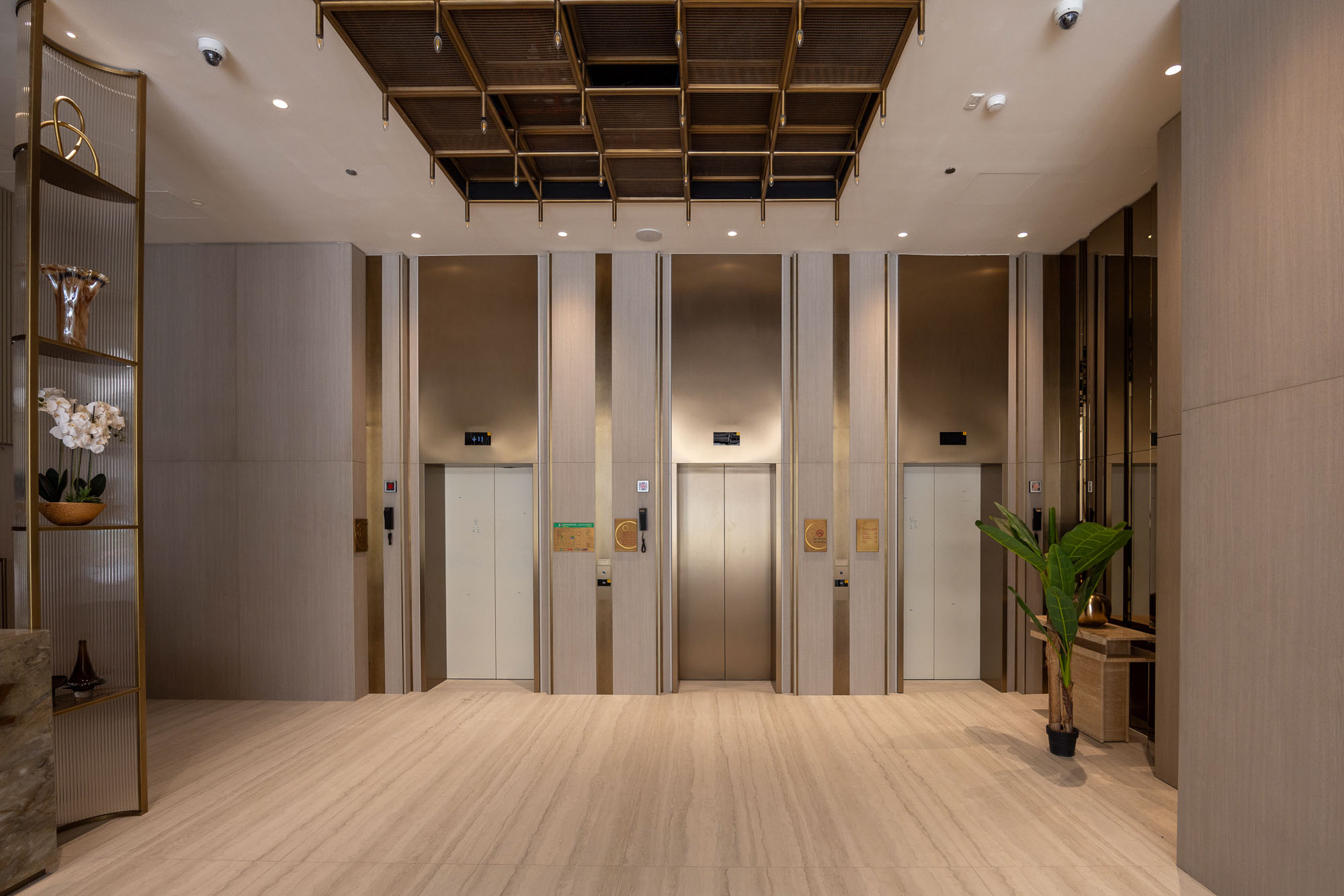 Pearl House By Imtiaz A modern lobby featuring four elevators, stylish decor, wooden paneling, and a potted plant in the corner.