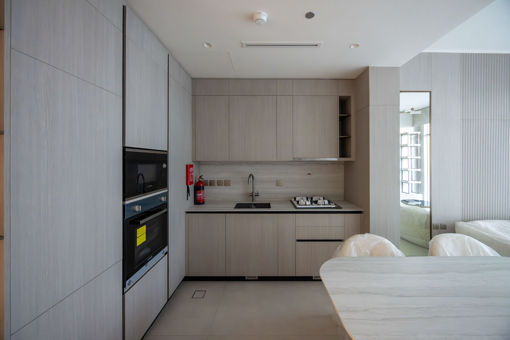 Pearl House By Imtiaz Modern kitchen with light wooden cabinets, gas stove, sink, and minimalist decor, featuring a round dining table.
