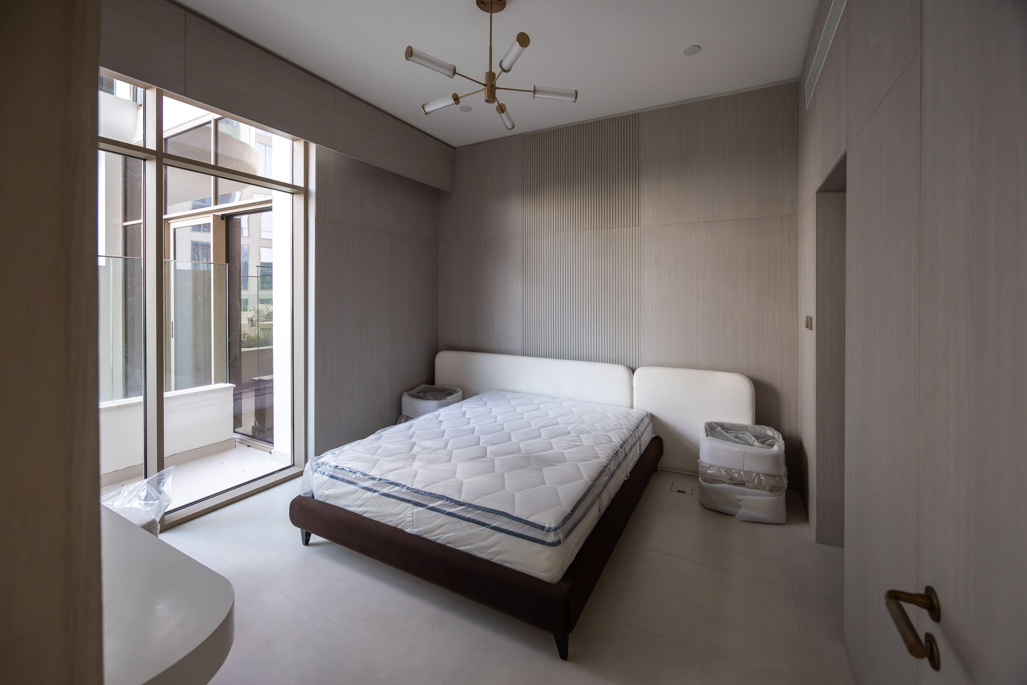 Pearl House By Imtiaz A minimalist bedroom featuring a queen-size bed, modern lighting, large windows, and muted wall colors.