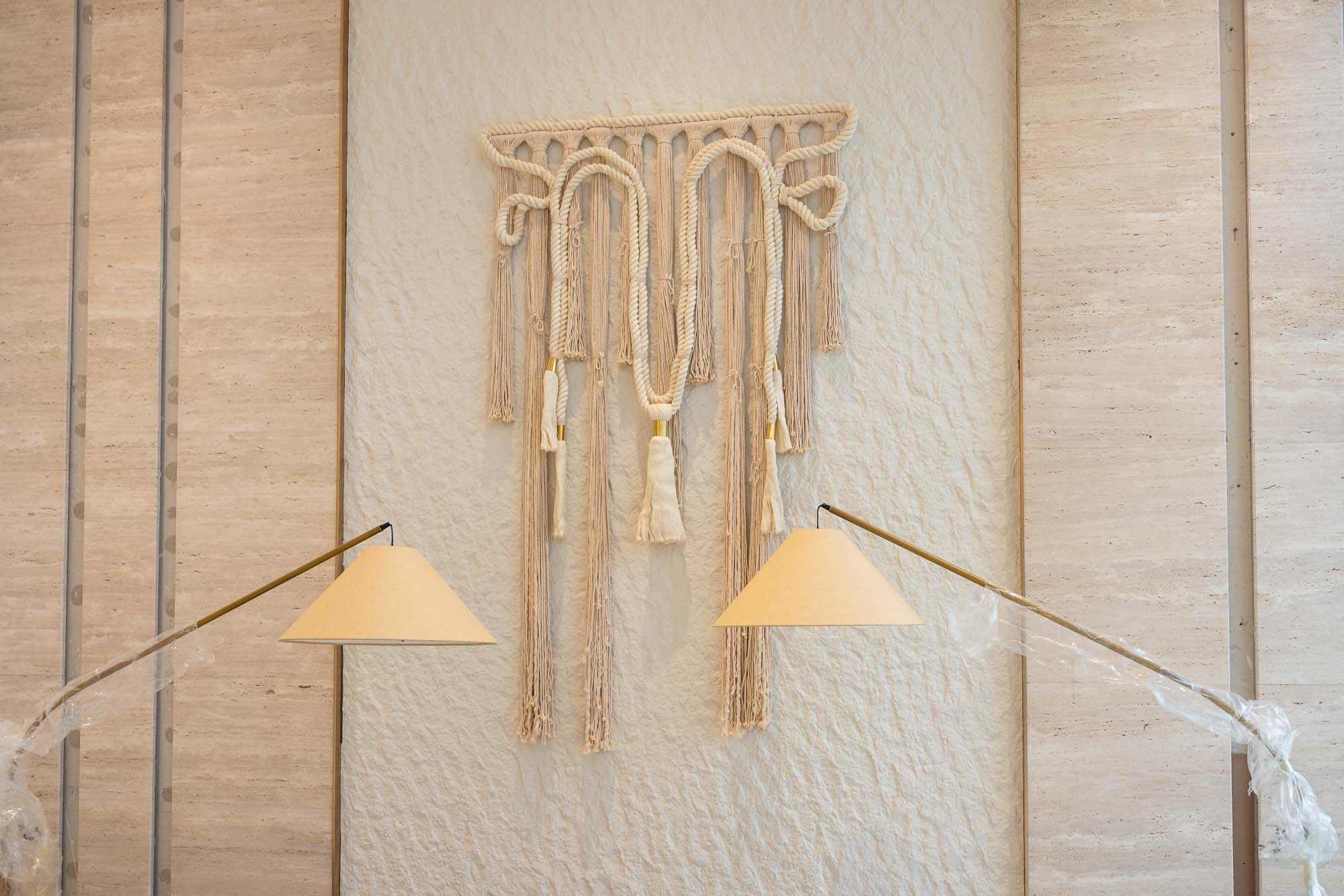 Beach Walk Residence A wall features a decorative macramé piece with two angled lamps at its sides, enhancing the modern interior design.