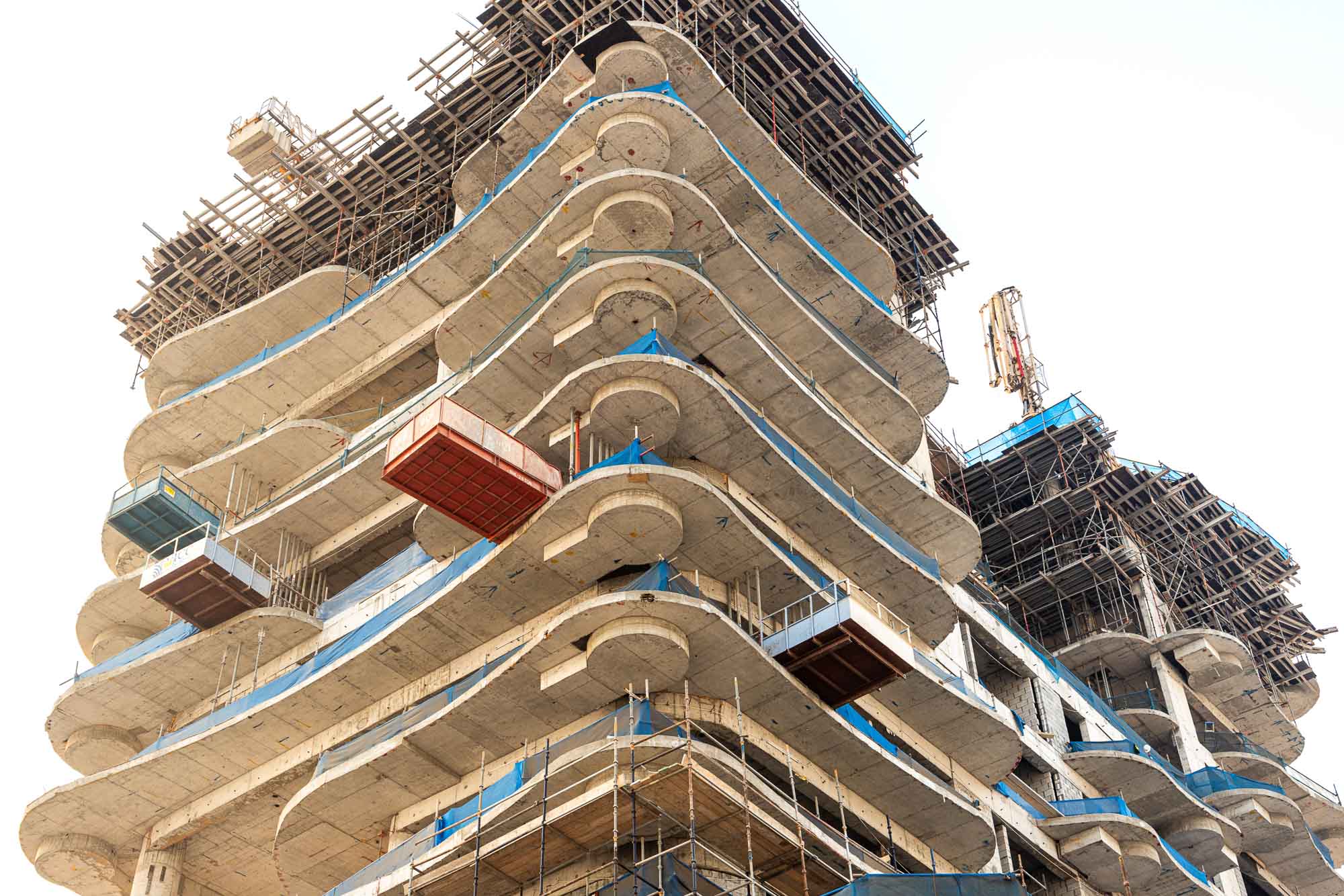 Beach Walk Iii By Imtiaz A modern building under construction featuring curved floors, scaffolding, and construction materials.
