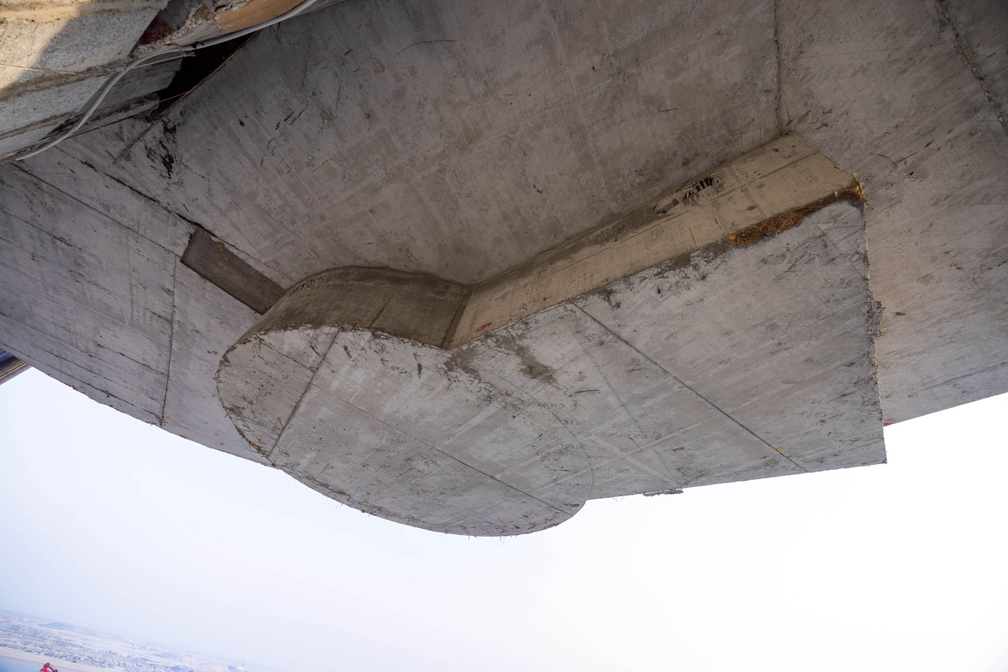 Beach Walk Iii By Imtiaz A close-up view of a concrete structure's underside, showcasing a curved and flat surface with visible texture.