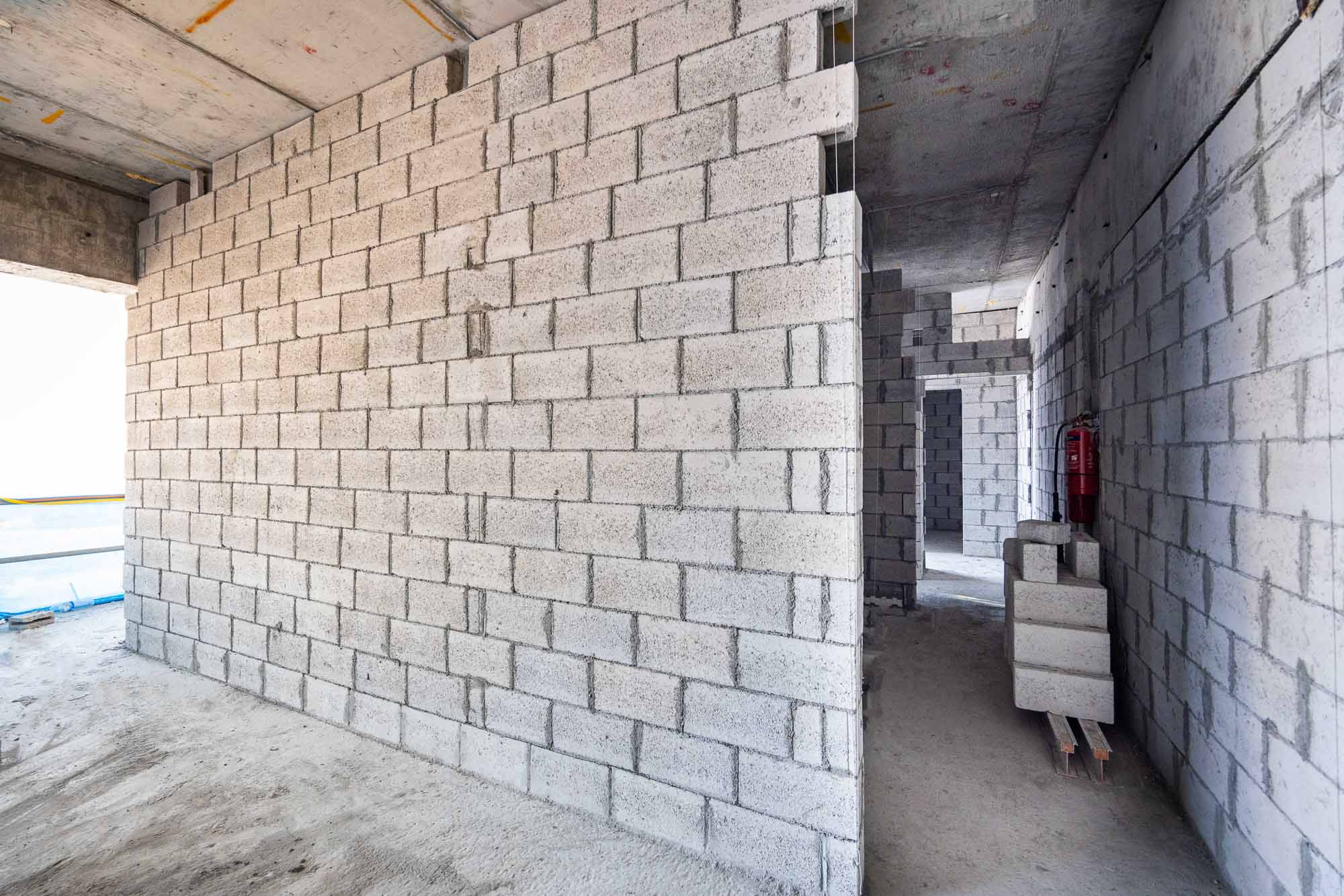 Beach Walk Iii By Imtiaz An unfinished building interior featuring concrete block walls and a clear pathway with blocks stacked nearby.