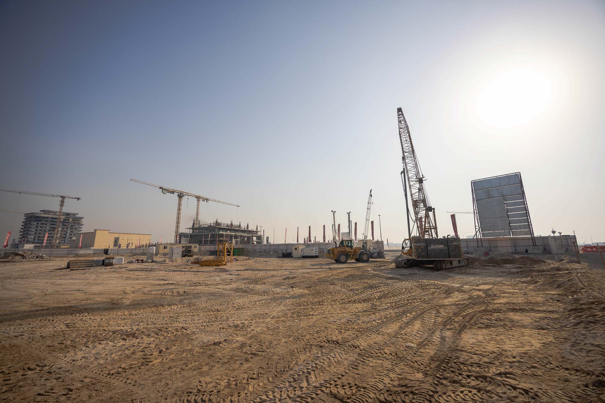Cotier House 2 By Imtiaz Construction site with cranes, heavy machinery, and unfinished buildings under a clear sky.