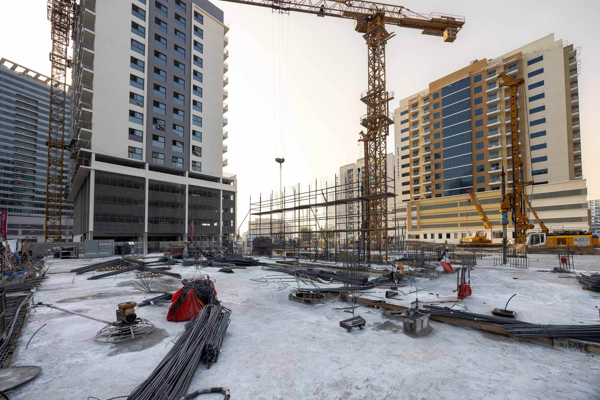 Cove Edition I By Imtiaz 1 Construction site with cranes, building materials, and two partially built apartment buildings in an urban area.