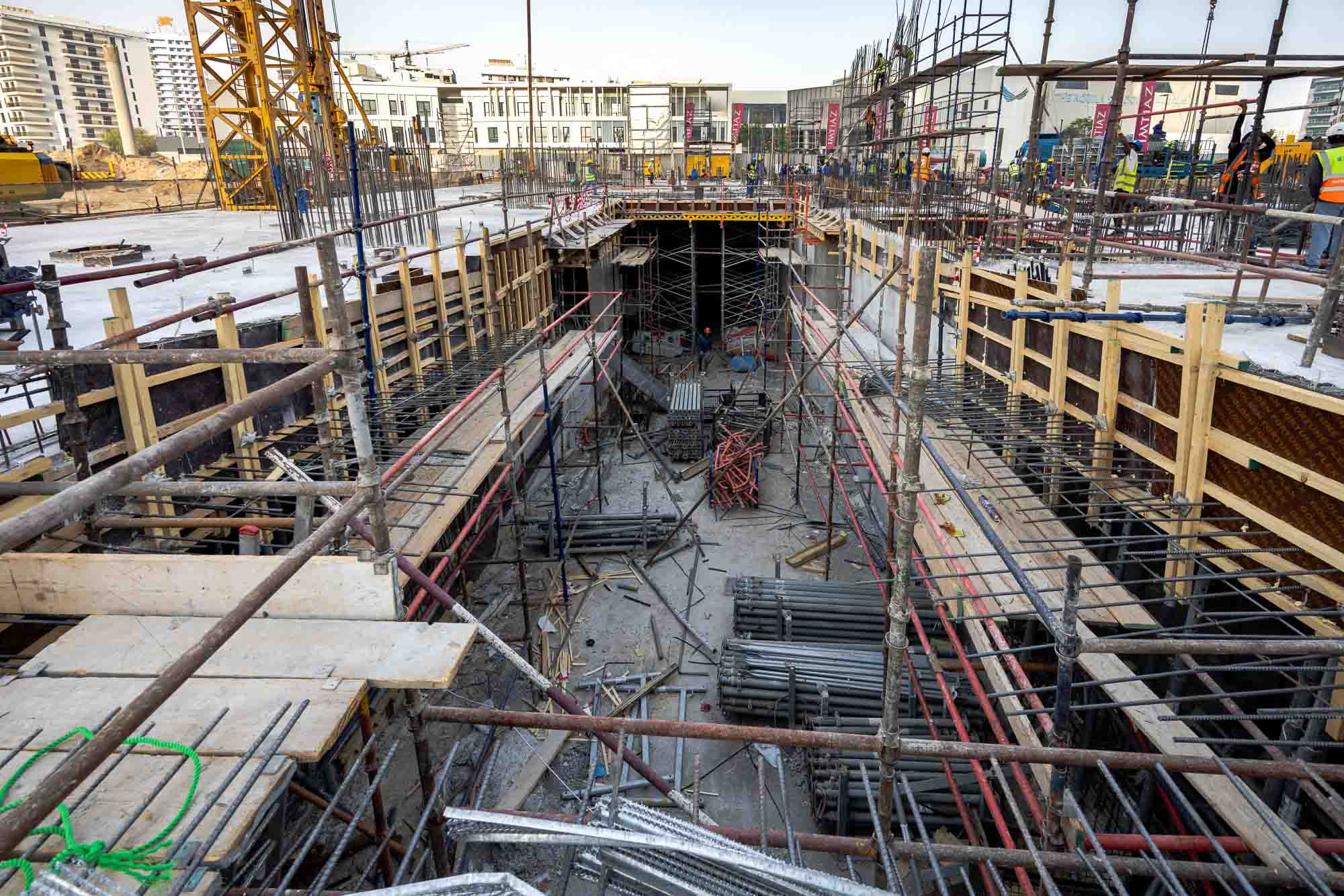 Cove Edition I By Imtiaz 1 A construction site with scaffolding, exposed beams, rebar, and building materials, showing ongoing structural work.