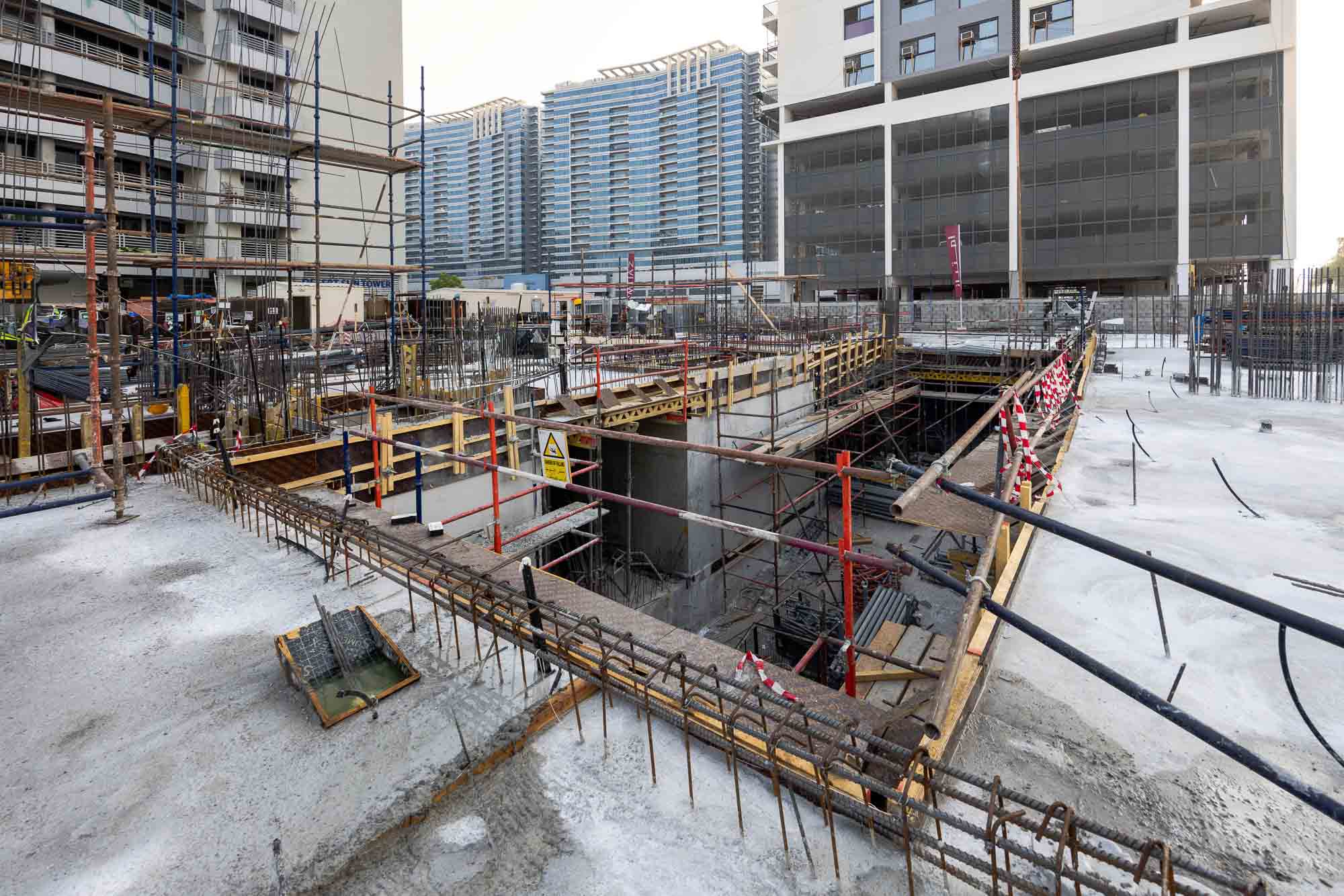 Cove Edition I By Imtiaz 1 A construction site featuring scaffolding, concrete structures, and a large pit under development in an urban area.