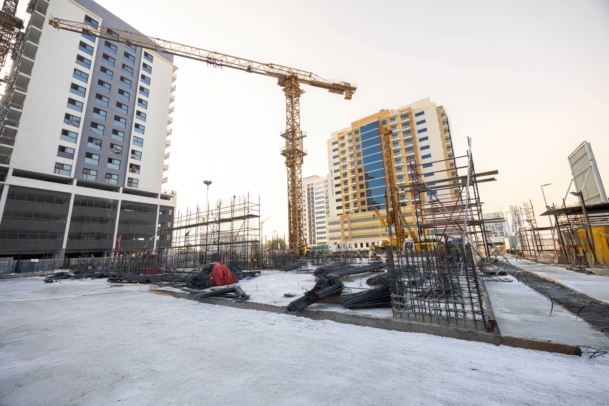 Cove Edition I By Imtiaz 1 Construction site with cranes, scaffolding, and infrastructure development near modern buildings.