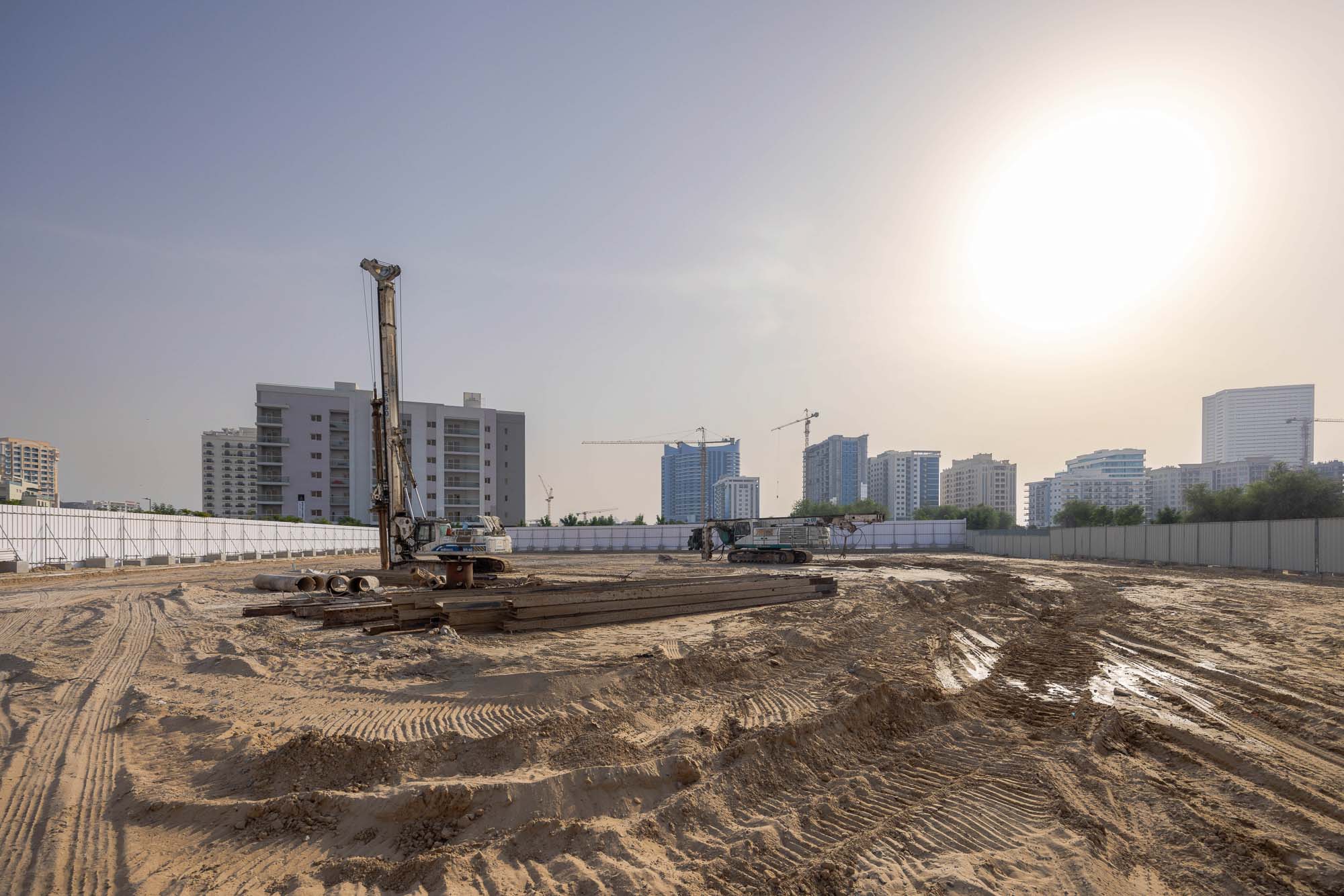 Cove Grand By Imtiaz Construction site with machinery, sand, and unfinished buildings under a clear sky at sunset.