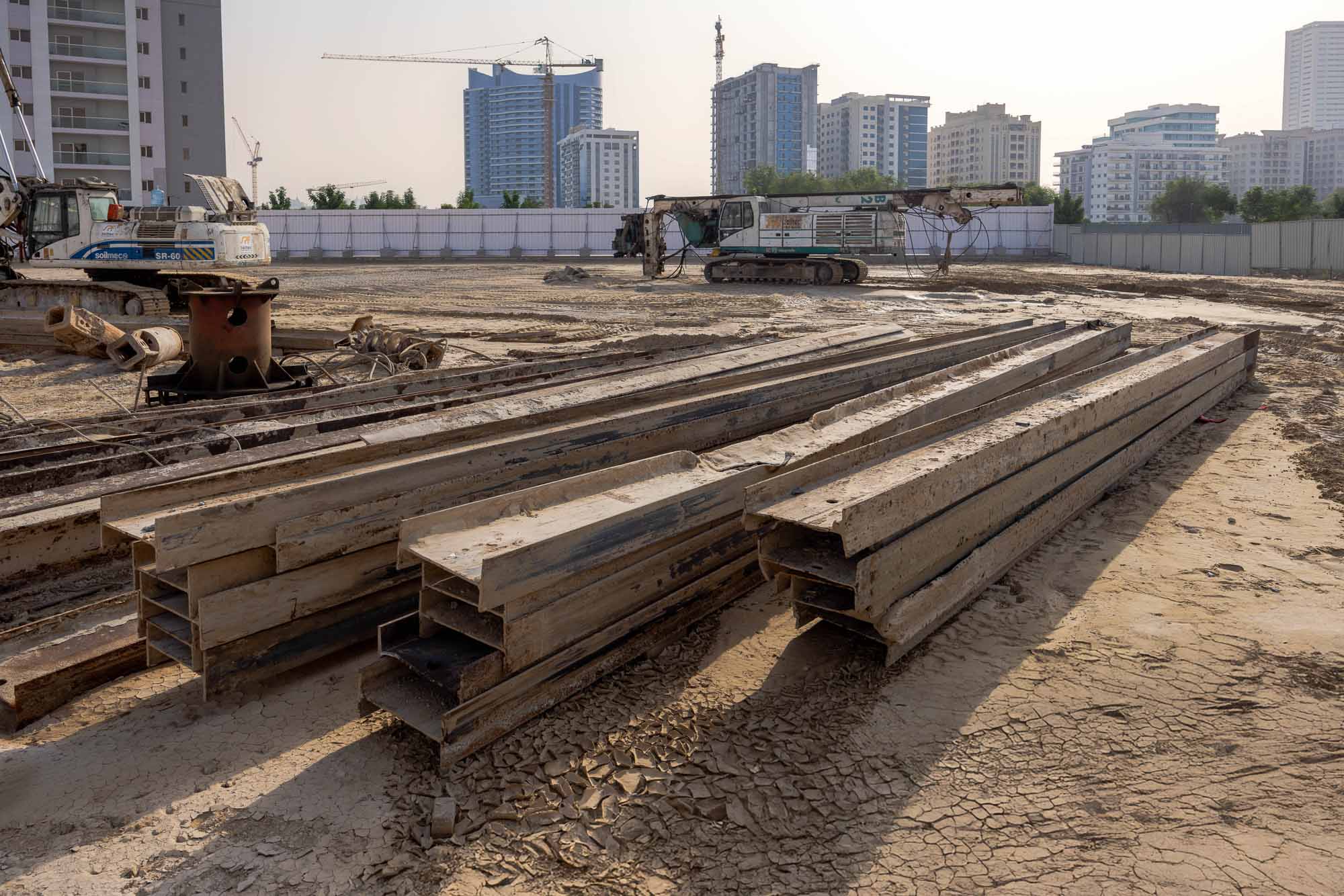 Cove Grand By Imtiaz Construction site with stacked steel beams and machinery, set against a backdrop of urban buildings.