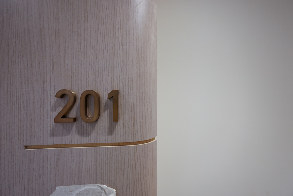 Beach Walk Residence Close-up of a wooden door featuring the room number "201" in gold lettering against a light background.