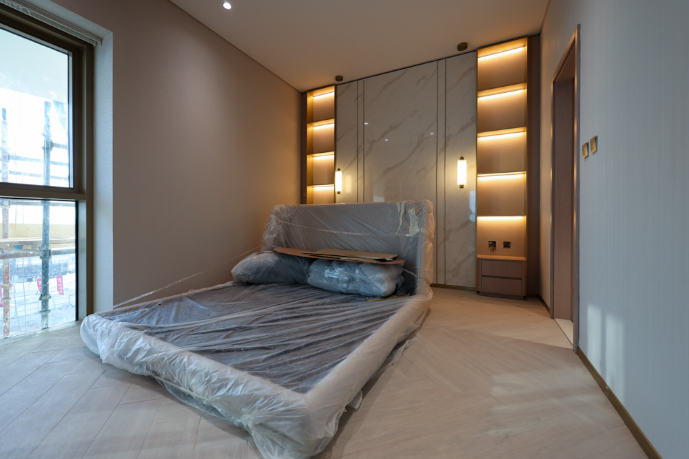 Beach Walk Residence A modern room featuring a bed covered in plastic wrap, elegant lighting, and a window with a view.