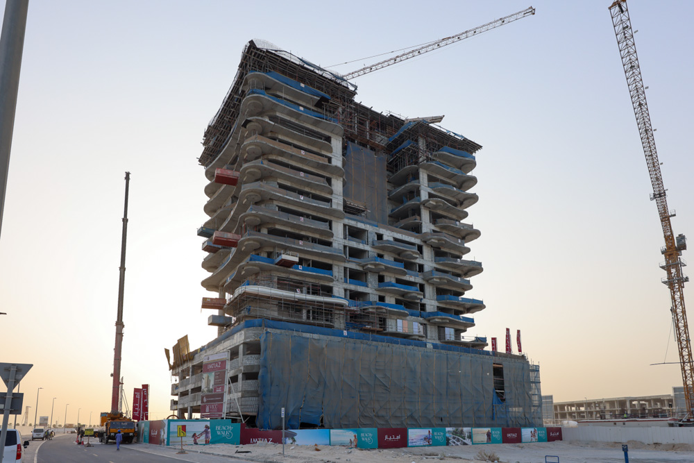 Beach Walk Iii By Imtiaz A high-rise building under construction with cranes, scaffolding, and a partially wrapped exterior at sunset.