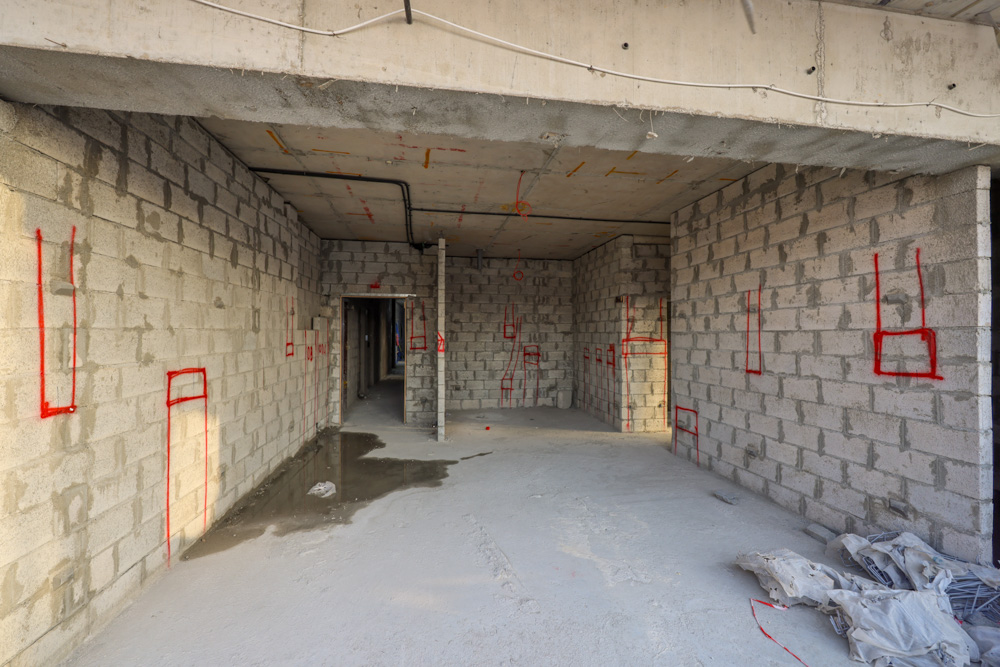 Beach Walk Iii By Imtiaz An unfinished interior space with concrete block walls marked in red, showing door and window outlines.