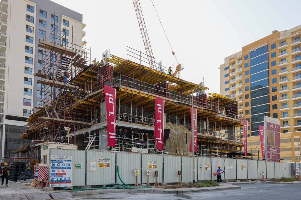 Cove Edition I By Imtiaz 1 Construction site with scaffolding, cranes, and workers, alongside modern buildings in an urban setting.