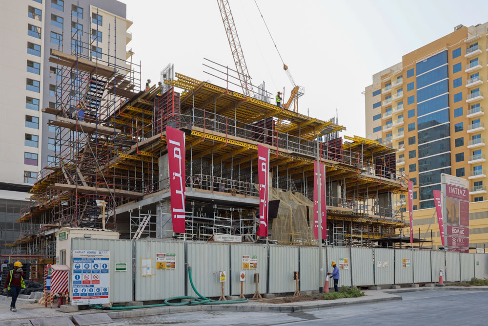 Cove Edition I By Imtiaz 1 A construction site featuring scaffolding, workers, and a partially built structure alongside nearby buildings.