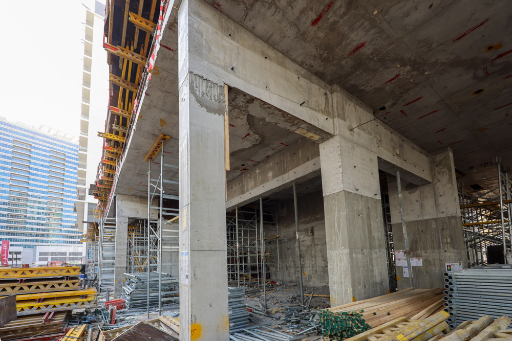 Cove Edition I By Imtiaz 1 Under-construction building with concrete pillars, scaffolding, and construction materials scattered in the site.