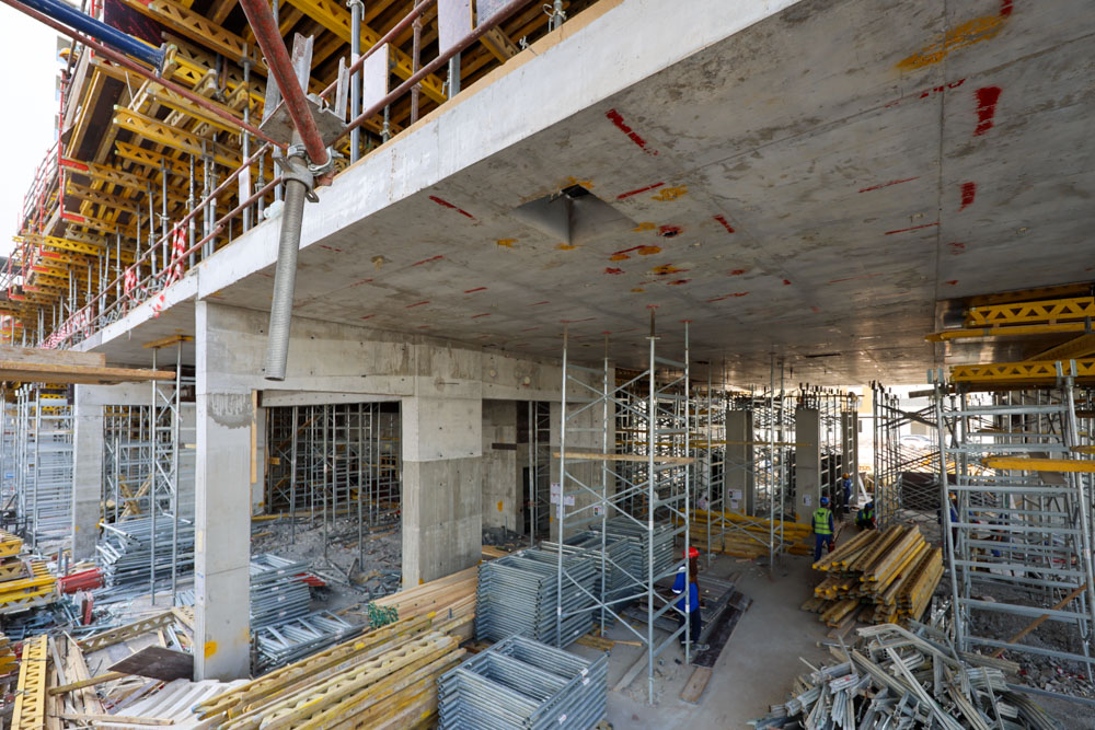 Cove Edition I By Imtiaz 1 Construction site with scaffolding, steel frames, and workers on-site amidst a concrete structure.