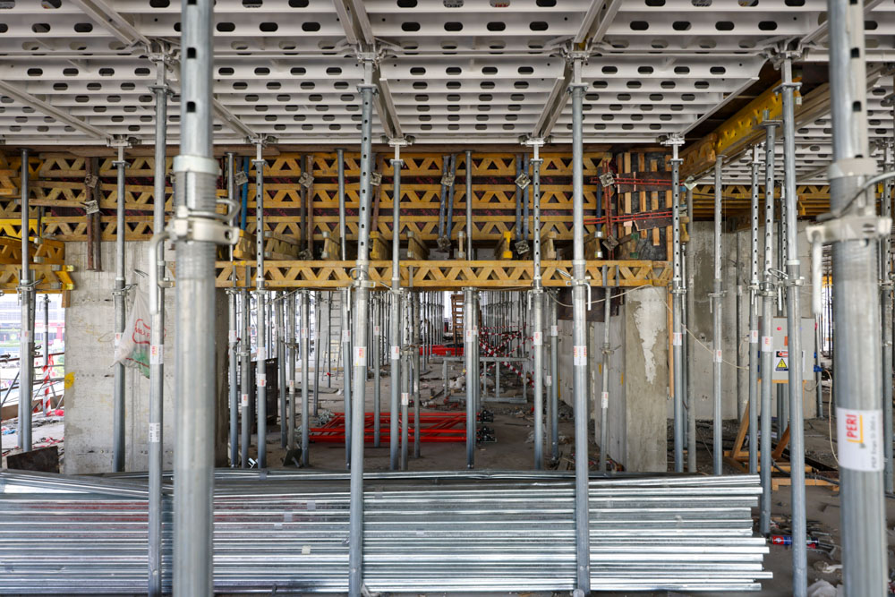 Cove Edition I By Imtiaz 1 Construction site interior showing scaffolding, support structures, and materials used for building.
