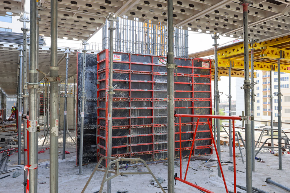 Cove Edition I By Imtiaz 1 Construction site featuring a concrete formwork system with red frames, scaffolding, and construction materials visible.