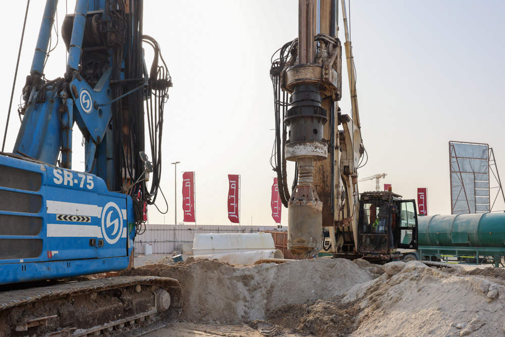 Cotier House 2 By Imtiaz Two large drilling machines are set up on a construction site with equipment and flags in the background.