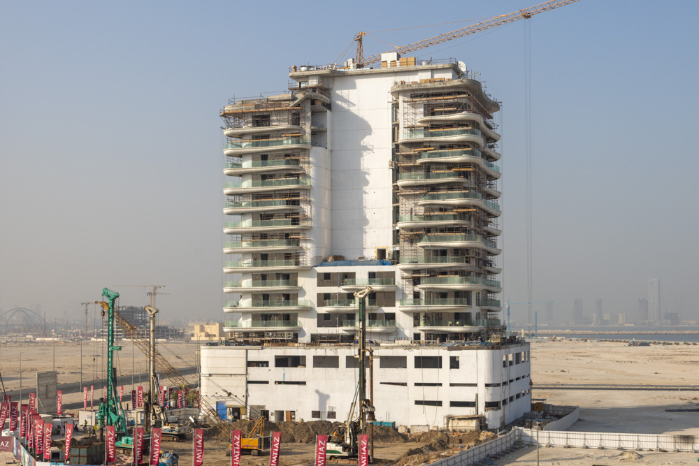 Beach Walk Residence A partially constructed high-rise building with scaffolding, surrounded by construction equipment in an urban area.
