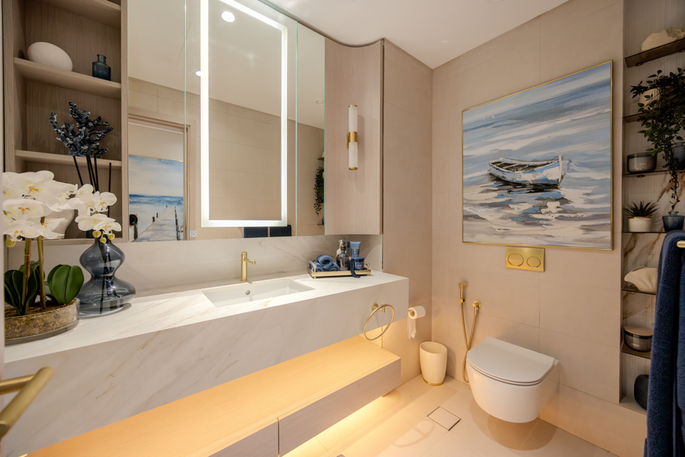 Beach Walk Residence A stylish bathroom featuring modern fixtures, a mirror with lighting, a boat painting, and decorative plants.